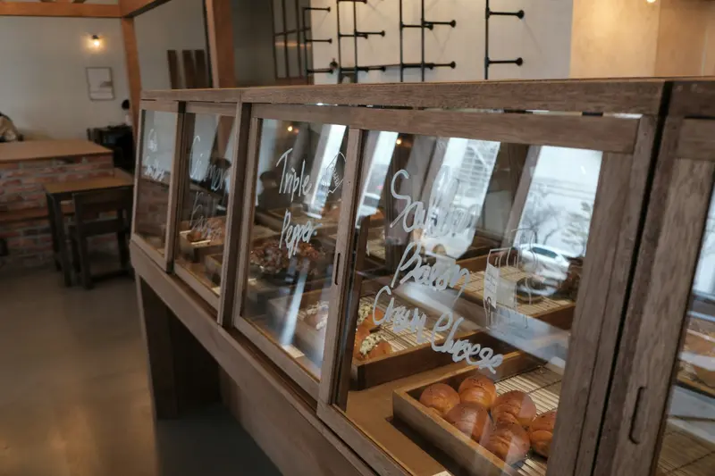 Vitrine en bois foncé et verre présentant des viennoiseries, avec des inscriptions peintes sur les vitres, dans une boutique.